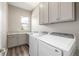 Bright laundry room with gray cabinets, granite counters, and new machines at 20148 E Windy Pine Pl, Parker, CO 80134