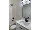 Modern bathroom includes tub and shower, decorative lighting, a bright white vanity, and a rectangular mirror at 5010 Golden Eagle Pkwy, Brighton, CO 80601