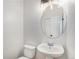 Charming powder room with pedestal sink, round mirror, modern lighting fixture, and neutral paint at 5010 Golden Eagle Pkwy, Brighton, CO 80601