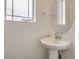 Stylish half-bathroom with pedestal sink, round mirror, and natural light from the window at 7260 Waterleaf Trl, Littleton, CO 80125