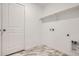 Bright laundry room with white walls, marble floors, a shelf, and hookups for washer and dryer at 7260 Waterleaf Trl, Littleton, CO 80125
