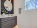 Stylish half-bathroom with modern vanity, decorative mirror, and a window offering natural light at 1290 W Quincy Cir, Englewood, CO 80110