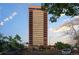 A tall building with balconies against a partly cloudy sky, seen from street level with trees and cars at 100 Park W Ave # 301, Denver, CO 80205