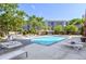 Bright outdoor pool area with lounge chairs, mature trees, and a nearby building on a sunny day at 100 Park W Ave # 301, Denver, CO 80205