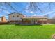 Wide backyard view with lawn, tree, and patio featuring brick accents connected to the home at 6611 Lamar St, Arvada, CO 80003