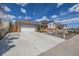 Exterior view of a house with a long driveway leading to an attached two-car garage and front yard at 6611 Lamar St, Arvada, CO 80003
