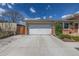Two-car garage with a long driveway, with landscaped front yard and brick accents at 6611 Lamar St, Arvada, CO 80003