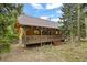Wood-sided cabin with large porch surrounded by lush, mature trees at 1673 Sinton Rd, Evergreen, CO 80439
