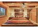 Cozy bedroom with wood paneling, beamed ceilings, a large bed and exterior view window at 1673 Sinton Rd, Evergreen, CO 80439