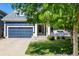 Beautiful blue home with covered porch and seating, mature shade trees, and a well-manicured front lawn at 1038 Mircos St, Erie, CO 80516