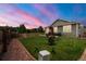 Scenic backyard with a green lawn, a wooden fence, lush trees, and a colorful sky at 2043 S Cathay Way, Aurora, CO 80013