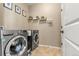 Convenient laundry room featuring modern washer and dryer, tile flooring, and storage shelves at 2043 S Cathay Way, Aurora, CO 80013