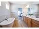 Bathroom with wood-look tile floor, standalone tub and view into the bedroom at 372 Castlemaine Ct, Castle Rock, CO 80104