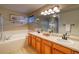 Bright bathroom with a shower, soaking tub, and a wood vanity with double sinks and mirrors at 3779 Aspen Hollow Ct, Castle Rock, CO 80104