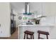 Modern kitchen featuring white cabinets, stainless steel appliances, a stylish range hood, and breakfast bar at 1330 Quebec St, Denver, CO 80220