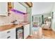 Home bar with wine refrigerator, custom cabinetry and lighting near living room at 18940 Pebble Beach Way, Monument, CO 80132
