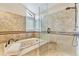 Beautiful bathroom featuring a soaking tub, glass enclosed shower with a built-in seat, and travertine tile at 18940 Pebble Beach Way, Monument, CO 80132