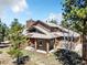 Inviting two-story home featuring wood siding, multiple gables, mature trees, and a bright red front door at 18940 Pebble Beach Way, Monument, CO 80132