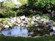 Lush backyard oasis with a rock-lined pond, waterfall feature, and mature trees at 13126 W Warren Cir, Lakewood, CO 80228