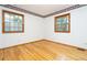 Bright bedroom with hardwood floors, white walls, two windows, and floral wallpaper trim at 29055 S Sunset Trl, Conifer, CO 80433