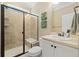 Bathroom featuring tiled walk-in shower with glass door, a built-in seat, and vanity with light-colored countertop at 17452 W 83Rd Pl, Arvada, CO 80007