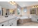 Bright bathroom with a dual sink vanity, tiled flooring, and soaking tub under a window at 17452 W 83Rd Pl, Arvada, CO 80007