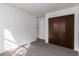Bedroom featuring neutral walls, carpet, and a closet with dark wood doors at 7484 E Princeton Ave, Denver, CO 80237