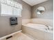 Bright bathroom features a soaking tub, neutral tile surround, and a window for natural light at 26155 E Euclid Dr, Aurora, CO 80016