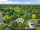 Aerial view of a home with a lush lawn, mature trees, a golf course nearby, and a tranquil neighborhood setting at 1 Club Ln, Littleton, CO 80123