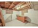 Unfinished basement room with tile flooring, paneled ceiling, work area, and stair access at 5355 S Windermere St, Littleton, CO 80120