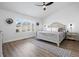 Bright bedroom with white walls, ceiling fan and wood-look floors, plus an upholstered king bed at 9877 Arthur Ln, Highlands Ranch, CO 80130