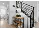 Bright entryway area with decoratively arranged console table and open staircase with black metal railing at 9877 Arthur Ln, Highlands Ranch, CO 80130