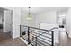 Well-lit second story hallway featuring rod iron railing, hanging light fixture and hard wood floors at 9877 Arthur Ln, Highlands Ranch, CO 80130