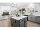 Open kitchen featuring an island with bar seating, gray cabinets, stainless steel appliances, and backyard access at 9877 Arthur Ln, Highlands Ranch, CO 80130