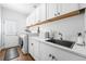 Neat laundry room with modern appliances, marble countertops, and white cabinetry at 9877 Arthur Ln, Highlands Ranch, CO 80130
