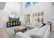 Bright living room with a large TV, white sectional, hardwood floors, and tall windows with plantation shutters at 9877 Arthur Ln, Highlands Ranch, CO 80130