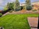 Picturesque backyard with terraced landscaping, tall trees, and a lawn at 2853 Black Canyon Way, Castle Rock, CO 80109