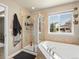 Bathroom featuring a large soaking tub, walk-in shower with glass doors, and a view of the neighborhood at 2853 Black Canyon Way, Castle Rock, CO 80109