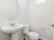 Elegant powder room with a pedestal sink and a modern round mirror at 6910 Merseyside Ln, Castle Pines, CO 80108