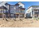 Attractive three-story townhome featuring gray and white tones and landscaping awaiting its final touches at 6910 Merseyside Ln, Castle Pines, CO 80108