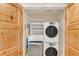 Efficient laundry closet featuring stacked washer and dryer and storage shelves with wood bi-fold doors at 1824 Pearl St # B, Boulder, CO 80302