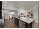 Contemporary kitchen featuring a white countertop island, dark cabinetry, hardwood floors, and open-concept layout to living room at 6802 S Uriah St, Aurora, CO 80016