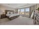 Bright main bedroom with a tray ceiling, three large windows, and neutral decor at 6802 S Uriah St, Aurora, CO 80016