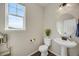 Well-lit powder room with a pedestal sink, decorative mirror, and a window at 6802 S Uriah St, Aurora, CO 80016