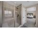 Bathroom featuring a glass enclosed shower, neutral tile, and access to main bedroom at 6802 S Uriah St, Aurora, CO 80016