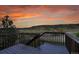 A wooden deck overlooks a scenic view of rolling hills under an orange sunset, offering a tranquil outdoor space at 3790 Aspen Hollow Ct, Castle Rock, CO 80104