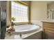 Elegant bathroom featuring a soaking tub with tile surround, perfect for relaxation and complemented by natural light at 3342 Springmeadow Cir, Castle Rock, CO 80109