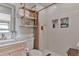 This bathroom features a wooden vanity, floating shelves, a shower with mosaic tile details, and white hexagon tile flooring at 10042 Hudson St, Thornton, CO 80229