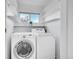 Bright laundry room featuring side-by-side washer and dryer with built in storage shelves and a window at 10057 Cedaridge Way, Highlands Ranch, CO 80129