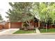 Charming brick home featuring mature trees, a two-car garage, and a well-maintained front yard at 10572 E Orchard Pl, Englewood, CO 80111